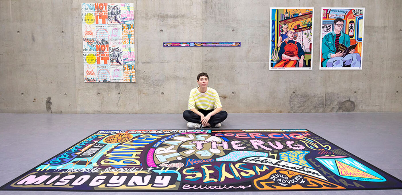 Artist Molly Hankinson sits on floor behind a large colourful mural. Two artworks hang on wall behind her.