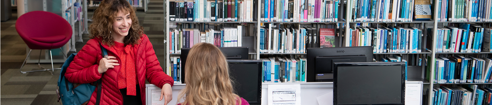 Two female students talking in the library